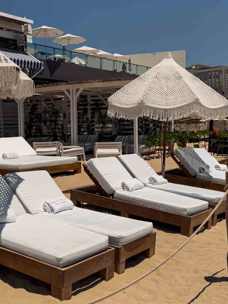 A beach bar with white sunbeds at the Medano Beach in Cabo San Lucas